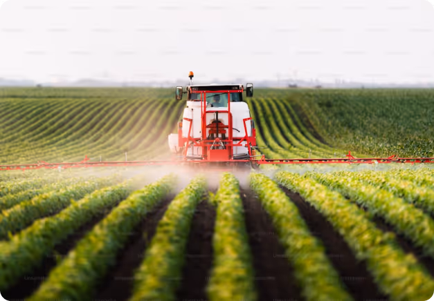 Farmer working on a tractor in a field at dusk with farming equipment attached.